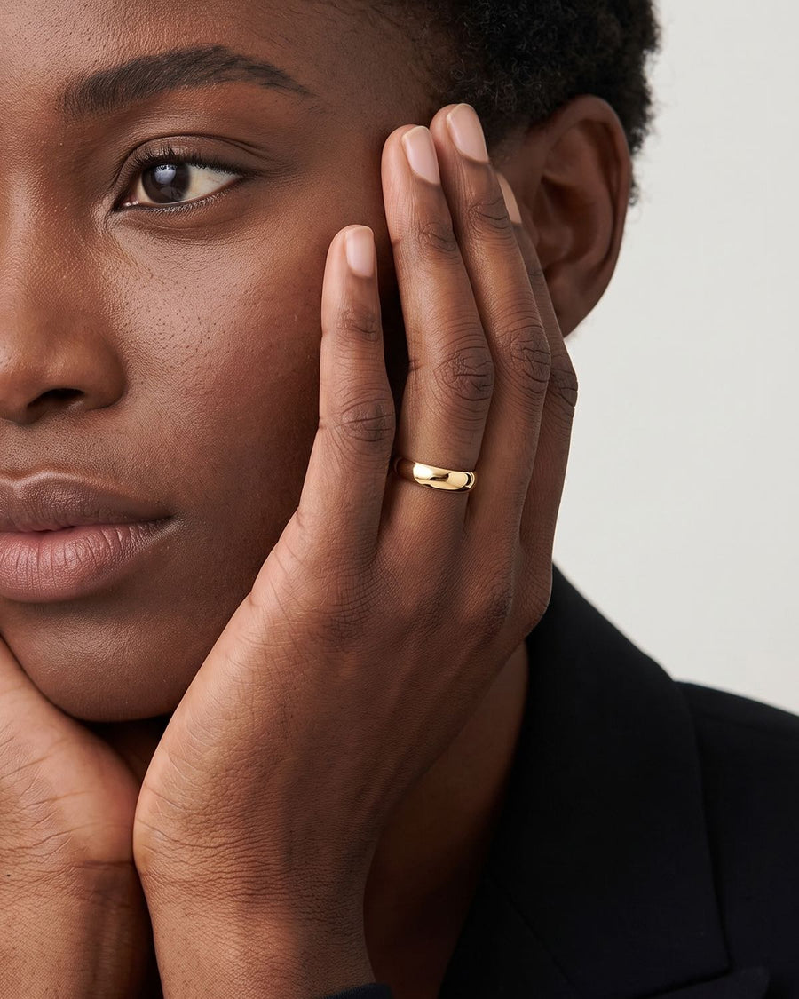 Model Image - 18k Gold 4mm minimalist band ring shown on the hand beside the face worn on model