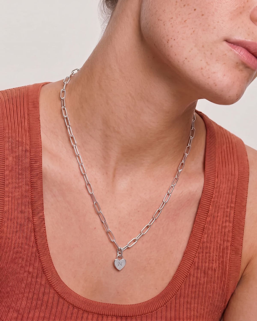 Model Image - Rhodium chunky chain necklace with a heart-shaped initial pendant shown at the neckline worn on model