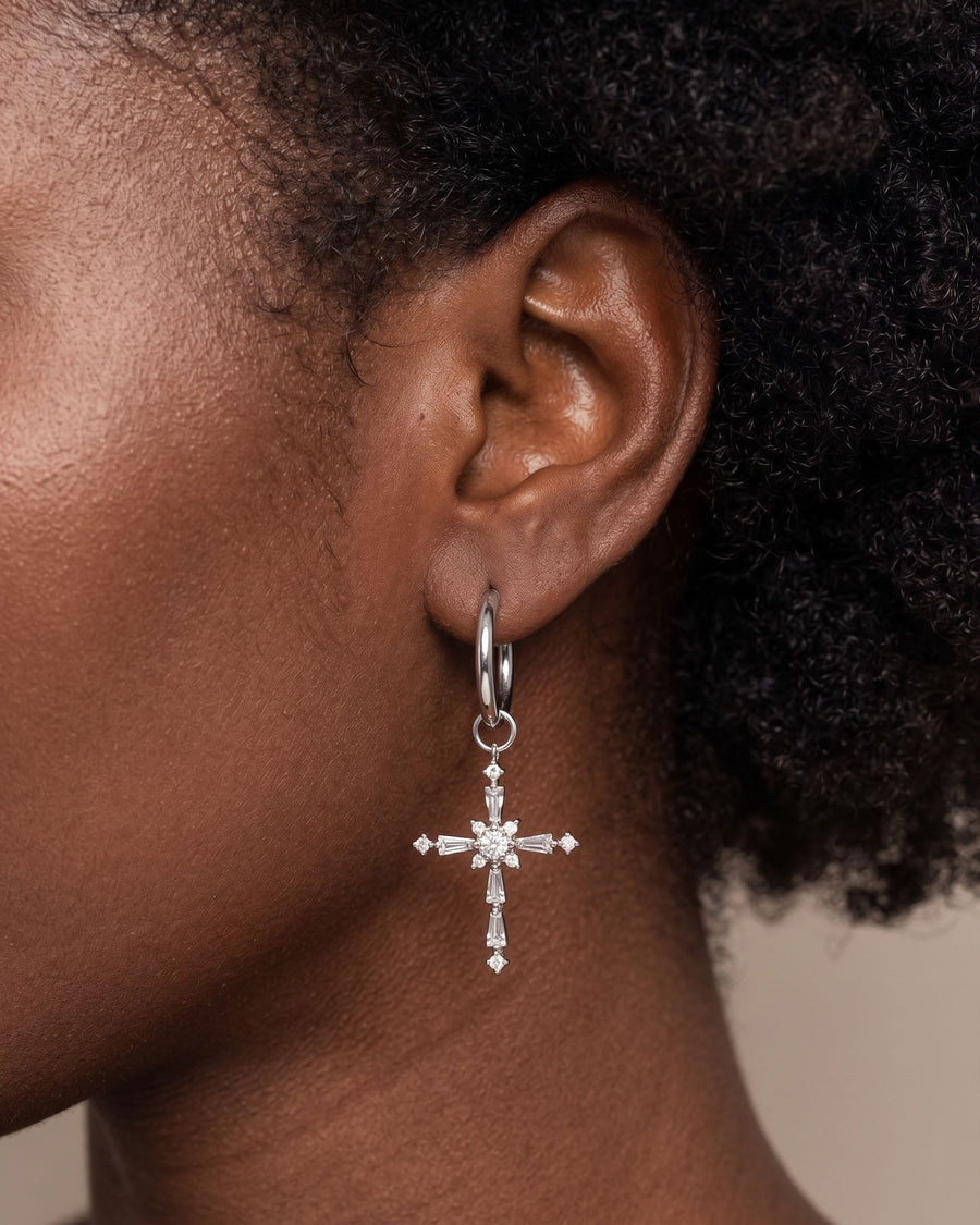 Model Image - Rhodium hoop earring with a dangling cross pendant and clear CZ accents worn on model