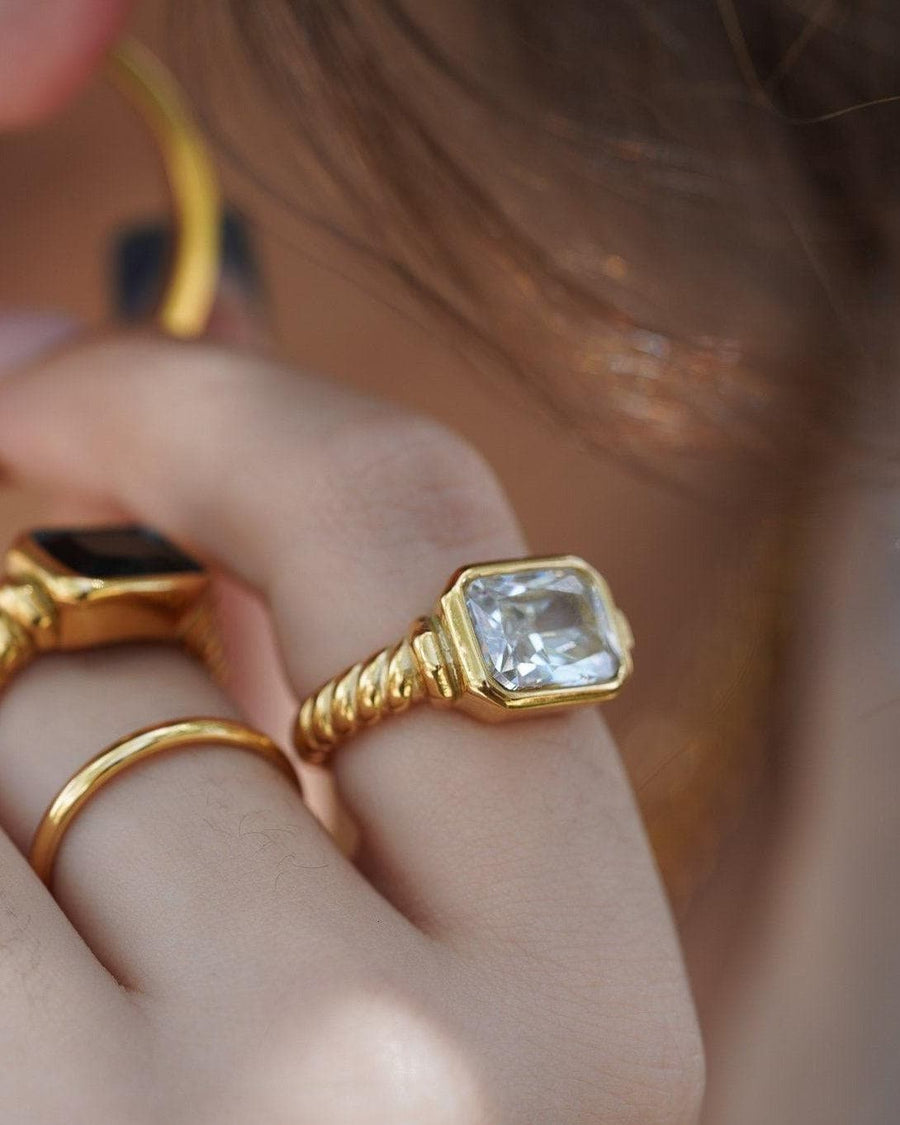 Model Image - Twisted signet ring with diamond on hand, styled with other gold-toned rings. worn on model
