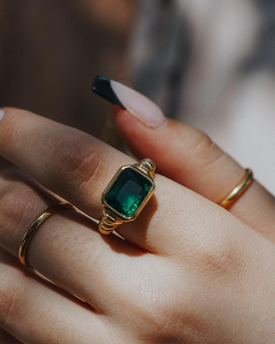 Model Image - Twisted Signet Ring with green emerald center stone and textured band styled with simple rings on the hand worn on model