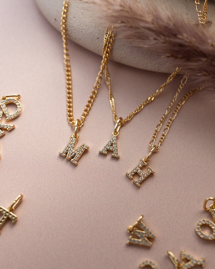 Model Image - layered gold letter charms on delicate chains styled at the neckline worn on model