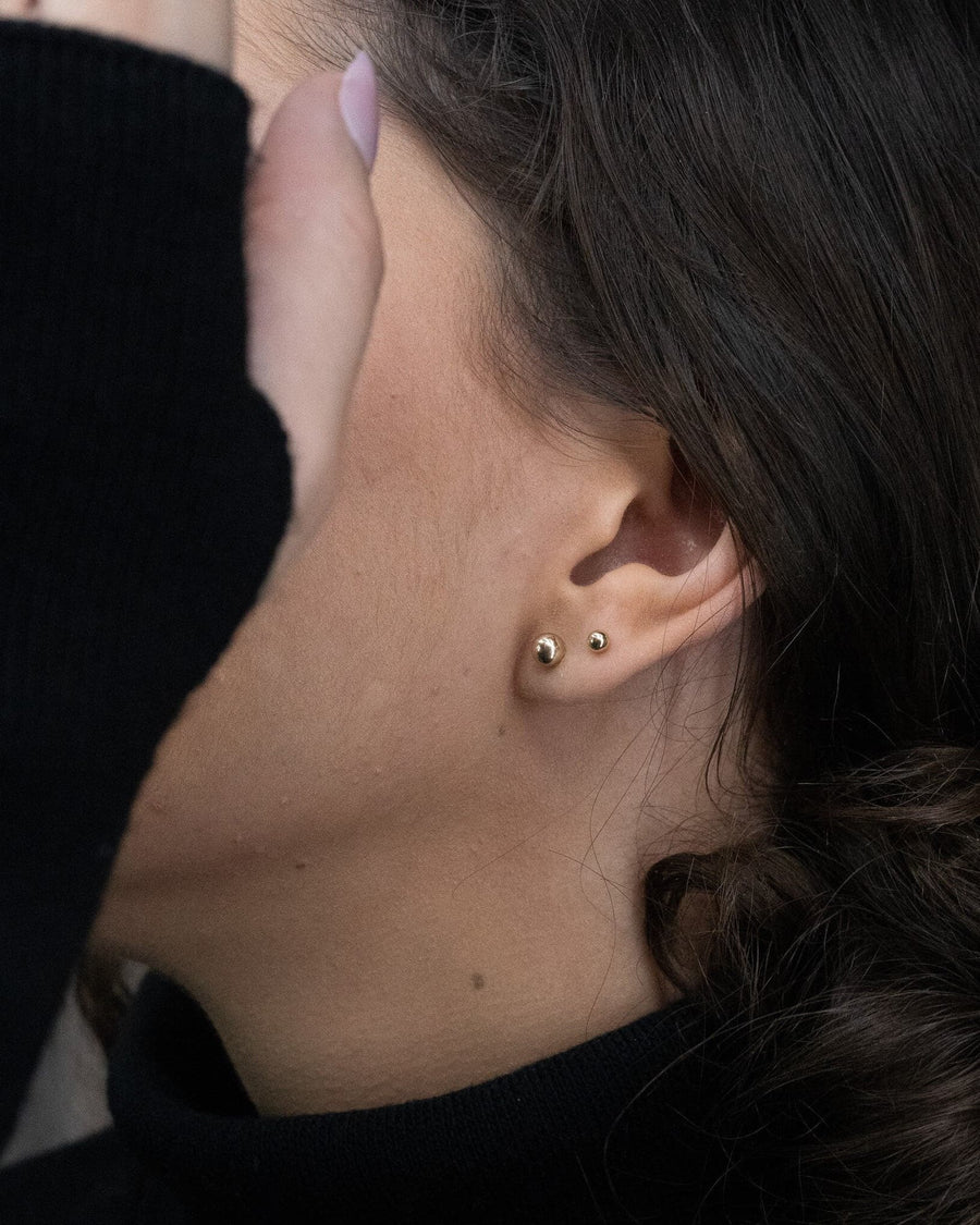 Model Image - Two small ball stud earrings styled side by side on the earlobe worn on model