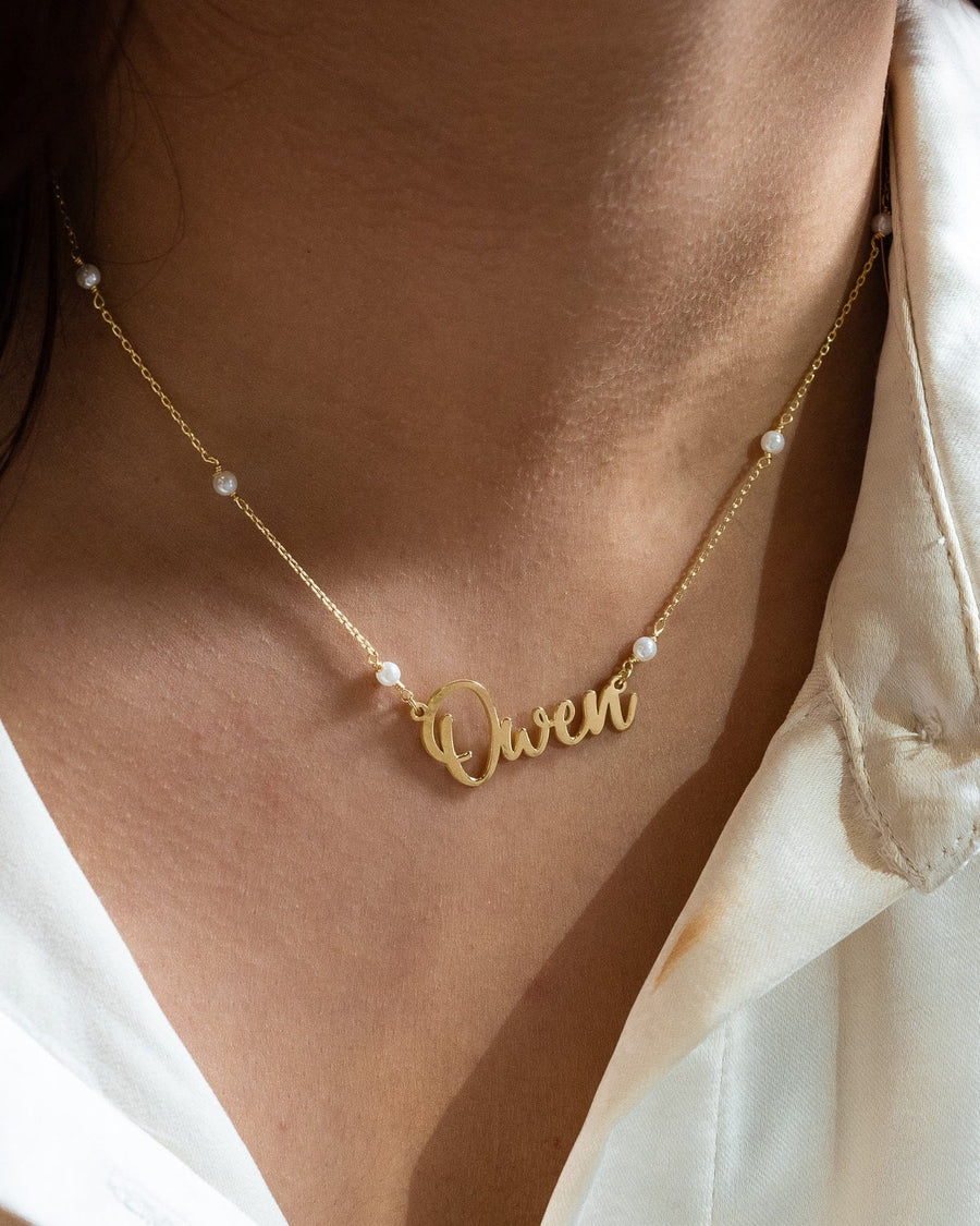 Model Image - 14k gold personalized name necklace on a pearl satellite chain styled at the neckline worn on model