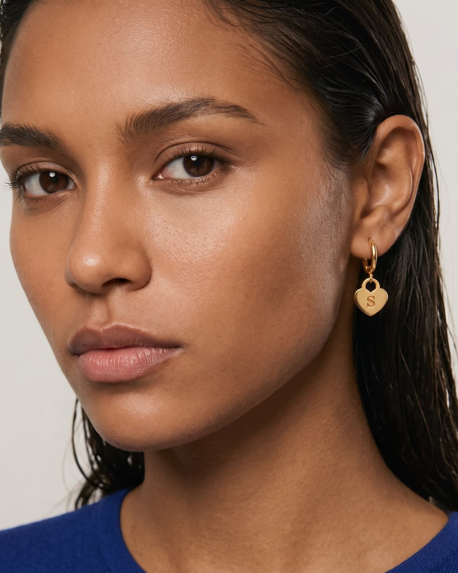Model Image - 14K Gold drop hoop earring with a heart pendant displaying the letter S worn on model