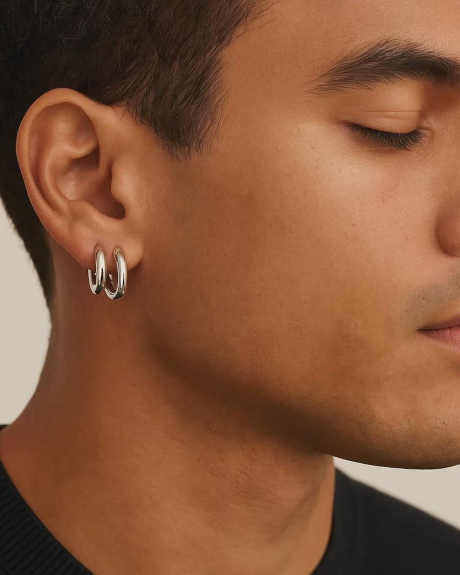 Model Image - A close-up side profile of a man wearing a pair of silver hoop earrings on his ear, against a plain light beige background.