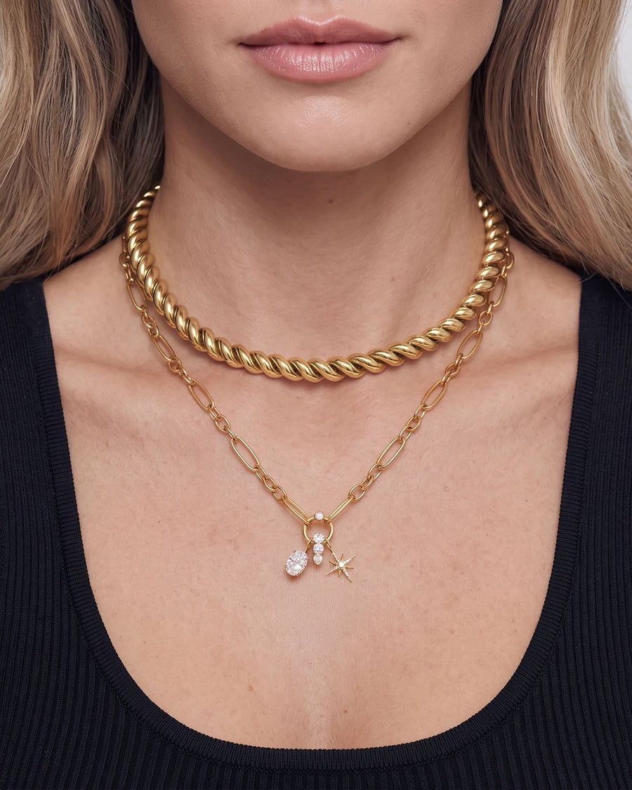 model image - A close-up of a model wearing a layered gold necklace set, featuring a thick twisted rope choker, a delicate paperclip chain with a small cross and clear crystal charm, and a thin chain with a small star charm.