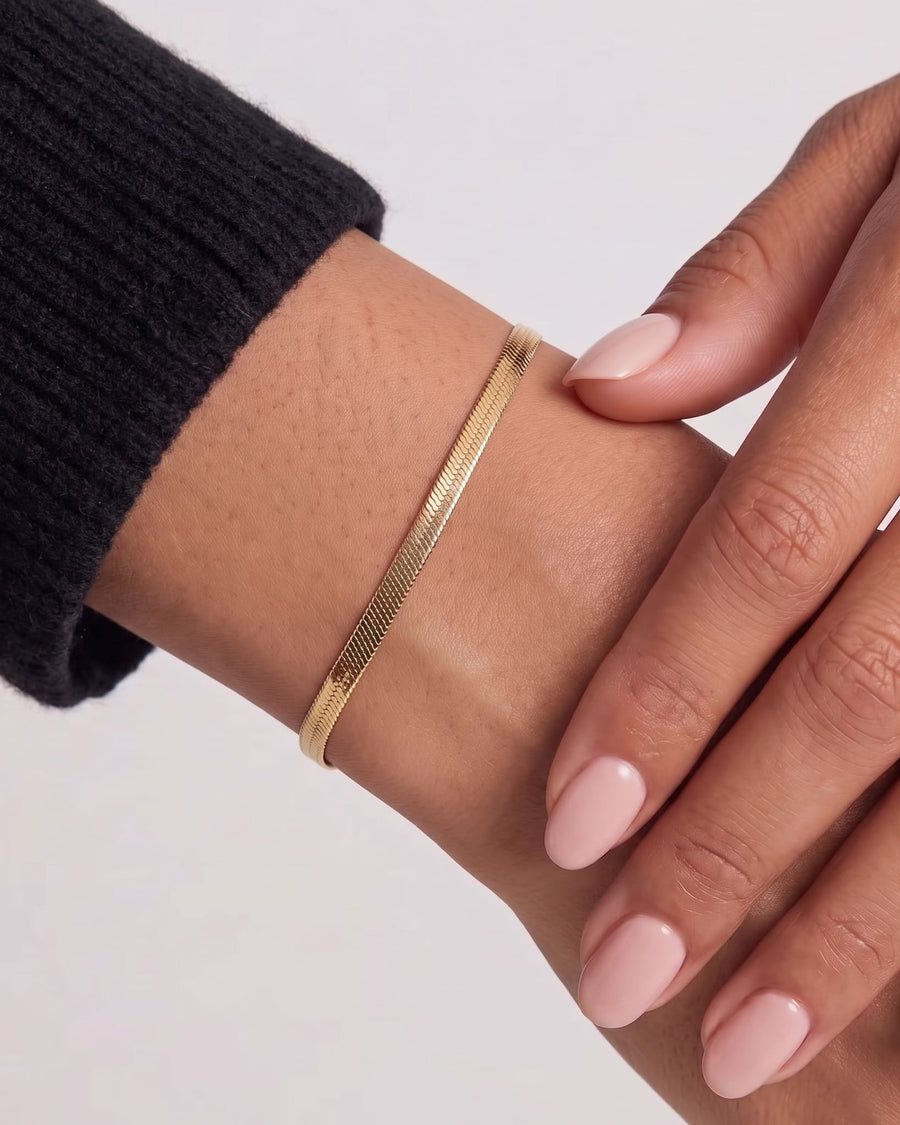 Model Image - 18k Gold herringbone bracelet with a flat chain pattern styled on the wrist worn on model
